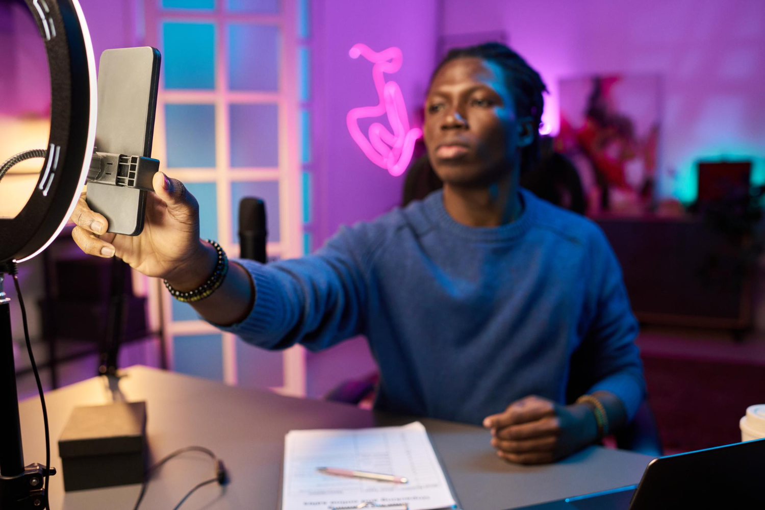 Criador de conteúdo gravando vídeo com smartphone e iluminação profissional, representando o desafio de produção para marcas que consideram o TikTok para empresas.